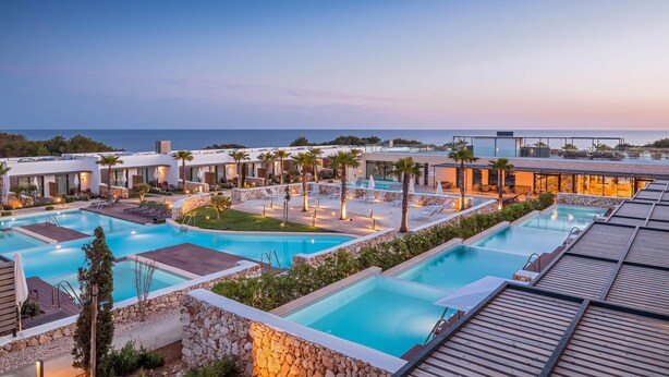 Un resort con varias piscinas, palmeras y edificios modernos.