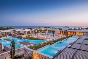 A resort with multiple swimming pools, palm trees, and modern buildings. - Barcelo Nura (Sant Lluis)