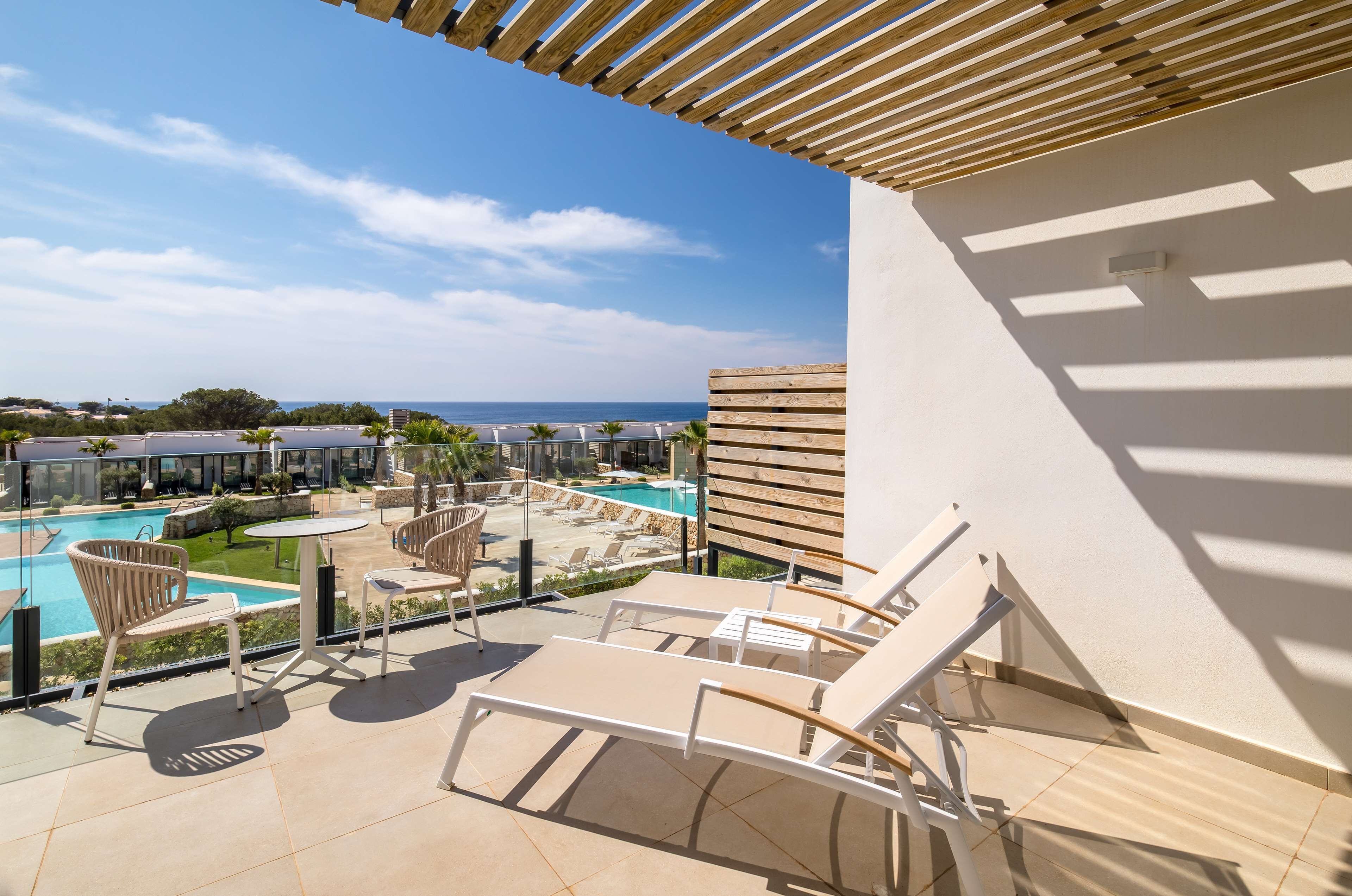 Eine Dachterrasse mit Lounge-Möbeln, einem Pool und Blick auf das Meer und andere Gebäude.