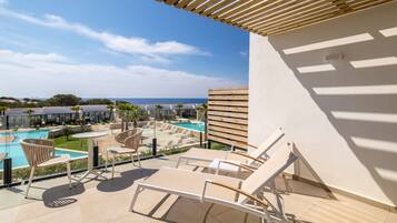 Eine Dachterrasse mit Lounge-Möbeln, einem Pool und Blick auf das Meer und andere Gebäude.