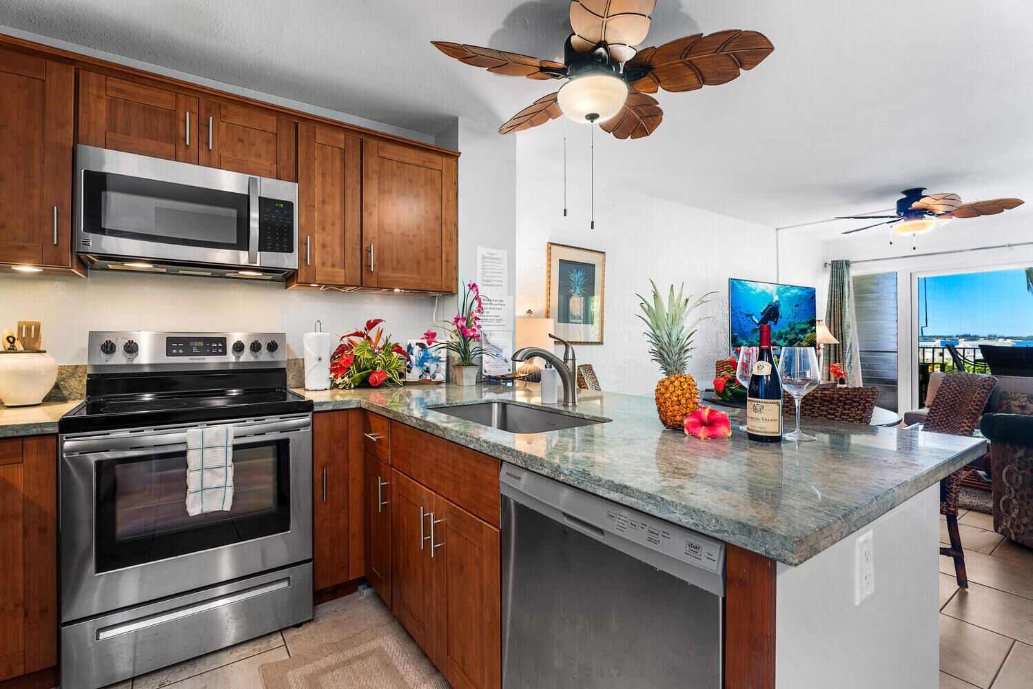 A modern kitchen with wooden cabinets, stainless steel appliances, a large island with a sink, and a ceiling fan.