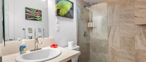 Un baño moderno con un lavamanos grande, cabina de ducha de vidrio y un inodoro.