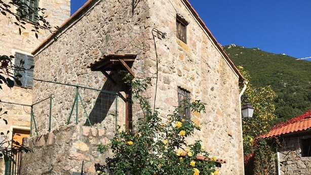 Un edificio de piedra con una puerta de madera y un pequeño balcón.