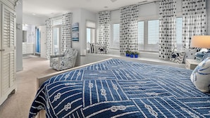 Un dormitorio con una cama grande, un ventilador de techo y vistas al baño.