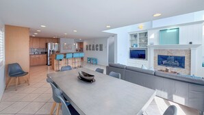 A modern kitchen with a dining area, a bar, and a living room with a fireplace. - 139H - Absolute Beach (Oxnard)