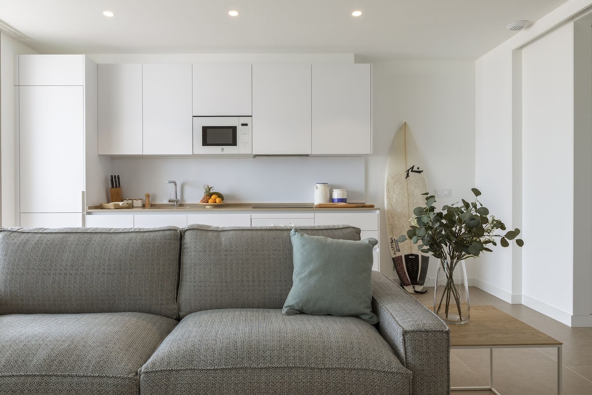 Una cocina moderna con armarios blancos, un microondas y una encimera de madera.