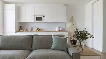 Een moderne keuken met witte kasten, een magnetron en een houten aanrecht.