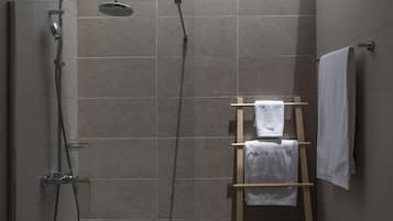 Un espace douche doté d’une porte en verre, d’un porte-serviettes en bois et d’une serviette accrochée au mur.