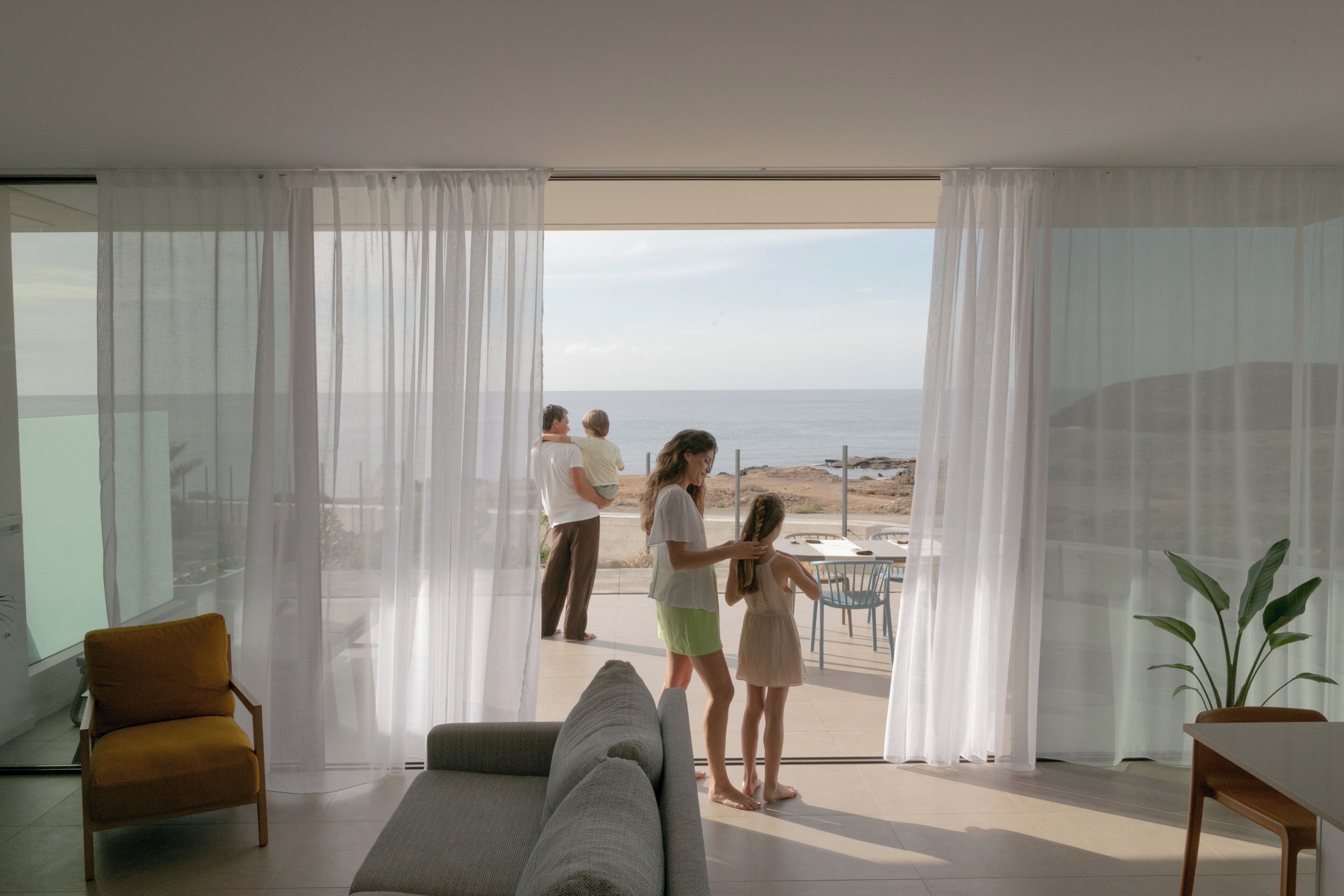 Un salon moderne doté d’une grande fenêtre donnant sur une plage.