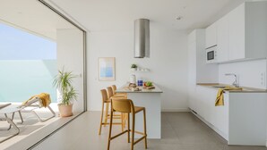 A modern kitchen with white cabinets, a central island, and a built-in microwave. - Kora Nivaria Beach (Arico)