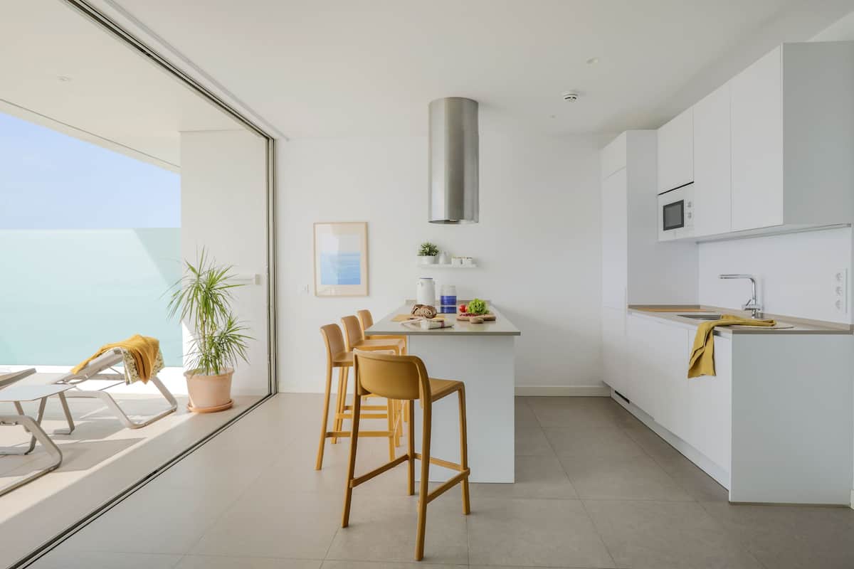 Una cocina moderna con armarios blancos, una isla central y microondas integrado.