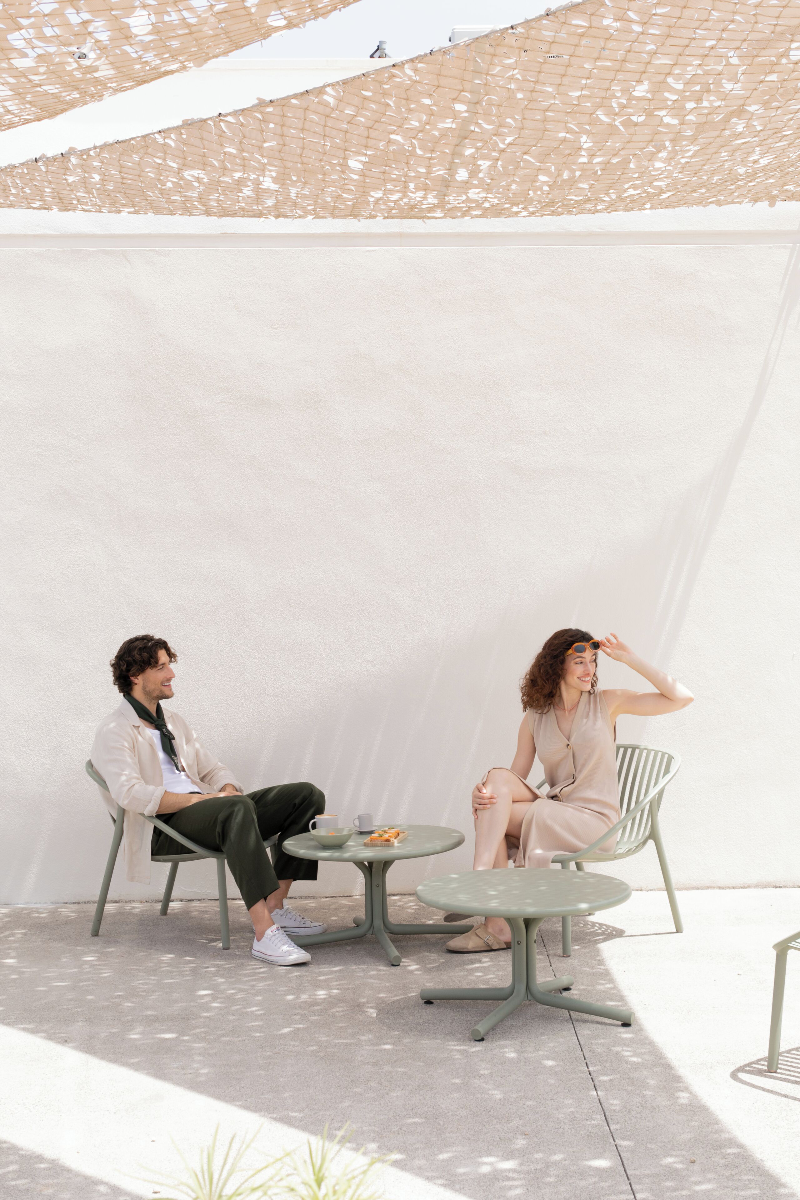 Two people seated at a table with a white backdrop.