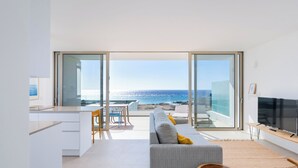 A modern living room with a large sliding glass door leading to a balcony with a sea view. - Kora Nivaria Beach (Arico)