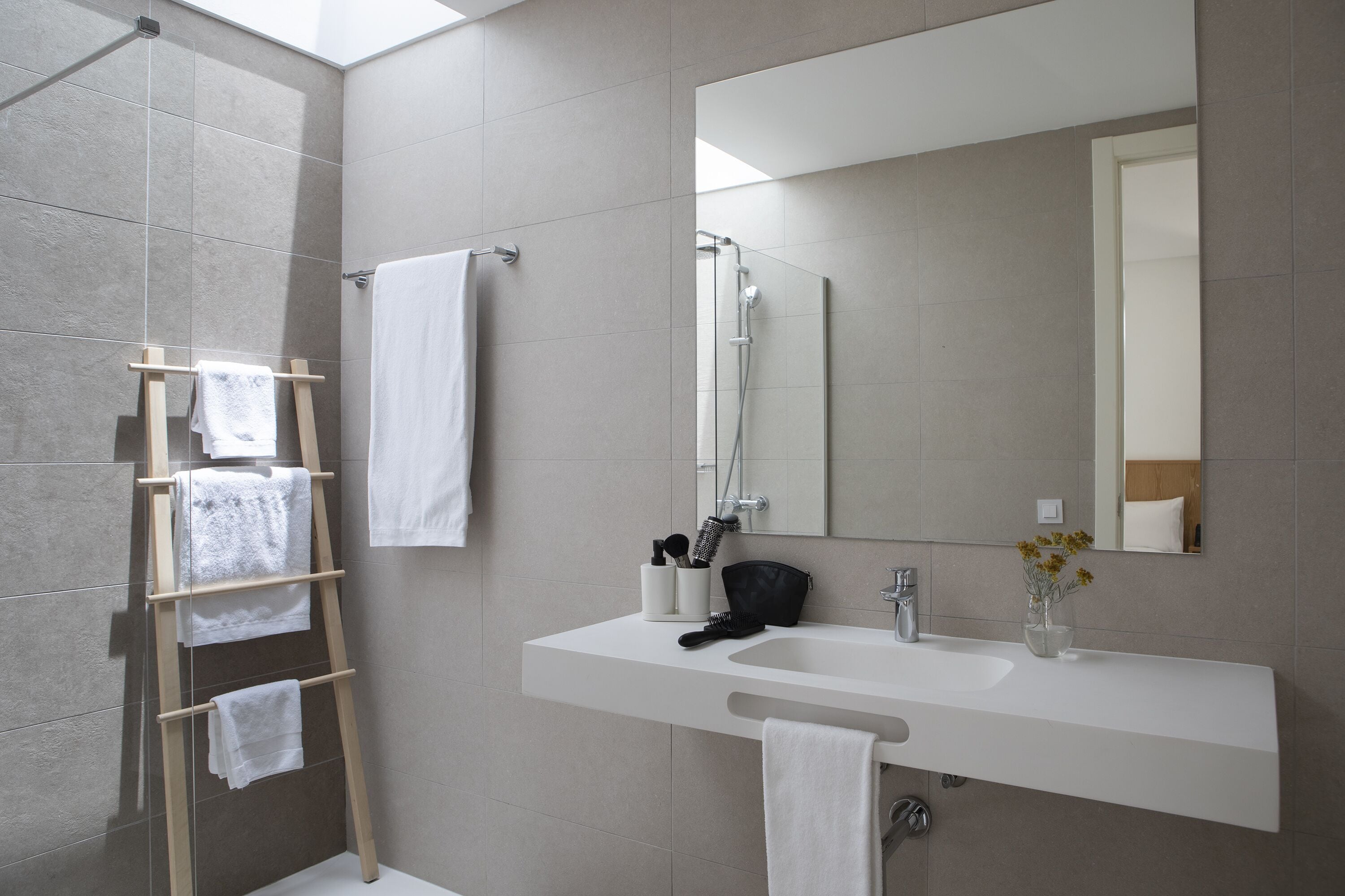 A modern bathroom with a shower, a sink with a mirror, and a towel rack.