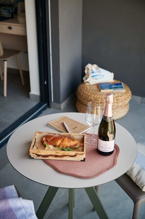 A round table with a sandwich, a glass of wine, and a bottle of champagne. - Irena Apartments (Konavle)