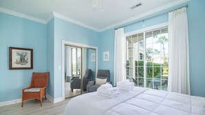 Une chambre avec un grand lit, une chaise, un miroir et une vue sur l’extérieur.