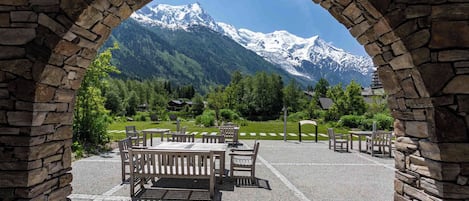An outdoor seating area with stone walls and a view of snow-capped mountains.