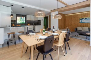 Une cuisine moderne avec un coin repas, un plancher en bois et des luminaires suspendus.