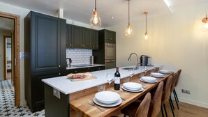 A modern kitchen with dark cabinets, a white countertop, and a wooden dining table set for six.