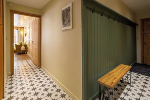 Um corredor com piso estampado, um banco de madeira, uma parede verde e uma porta.
