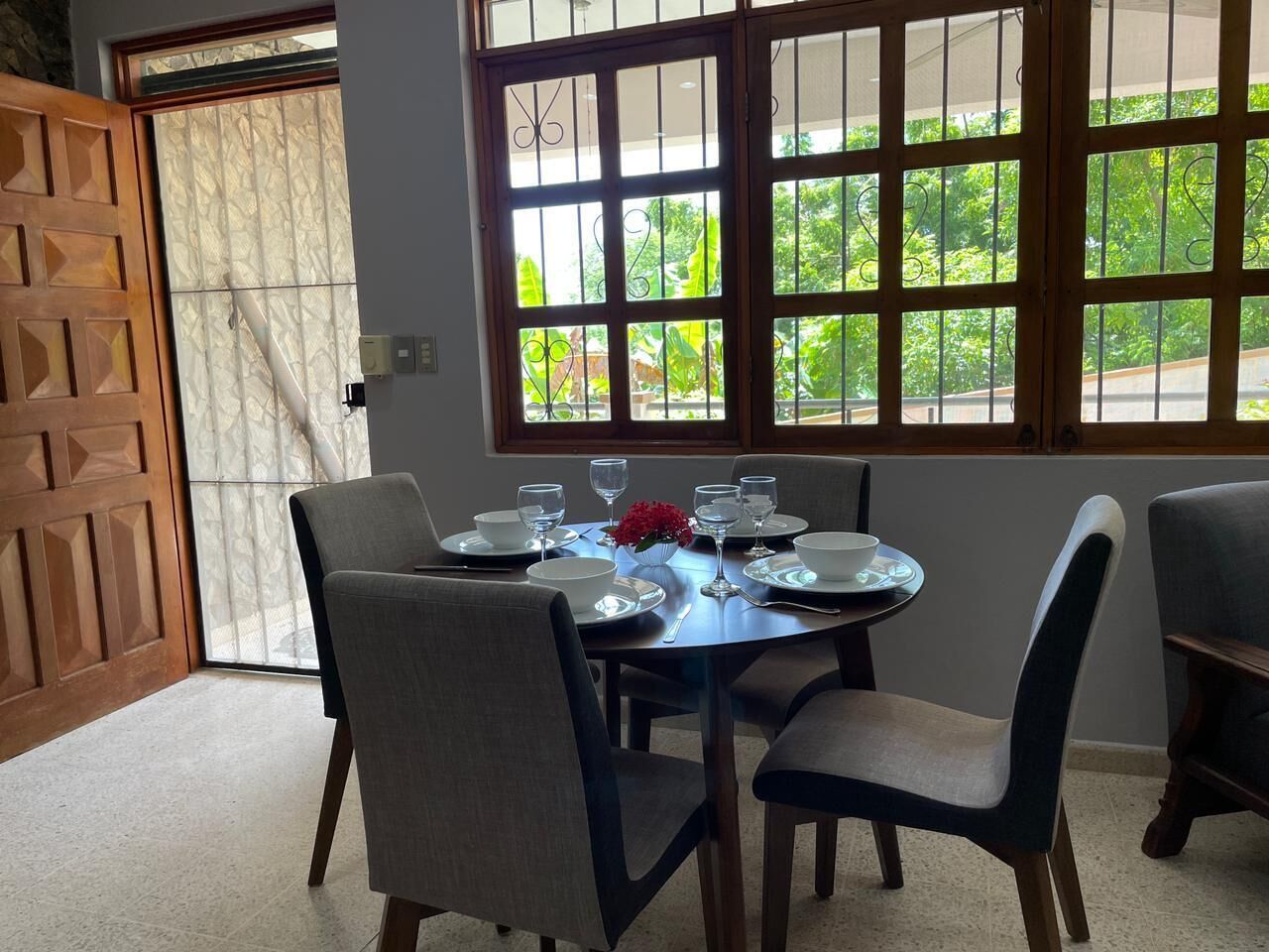 A dining area with a round table set for four, surrounded by chairs.