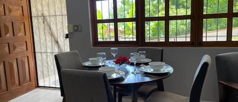 A dining area with a round table set for four, surrounded by chairs.