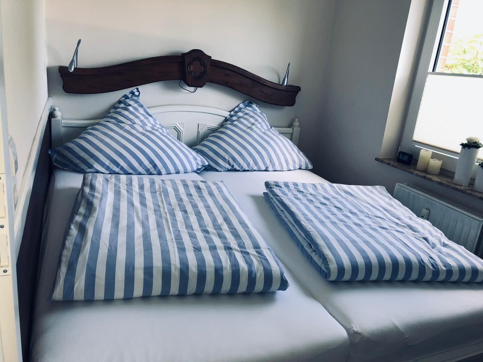Un lit bien fait, avec des oreillers à rayures et une tête de lit en bois.
