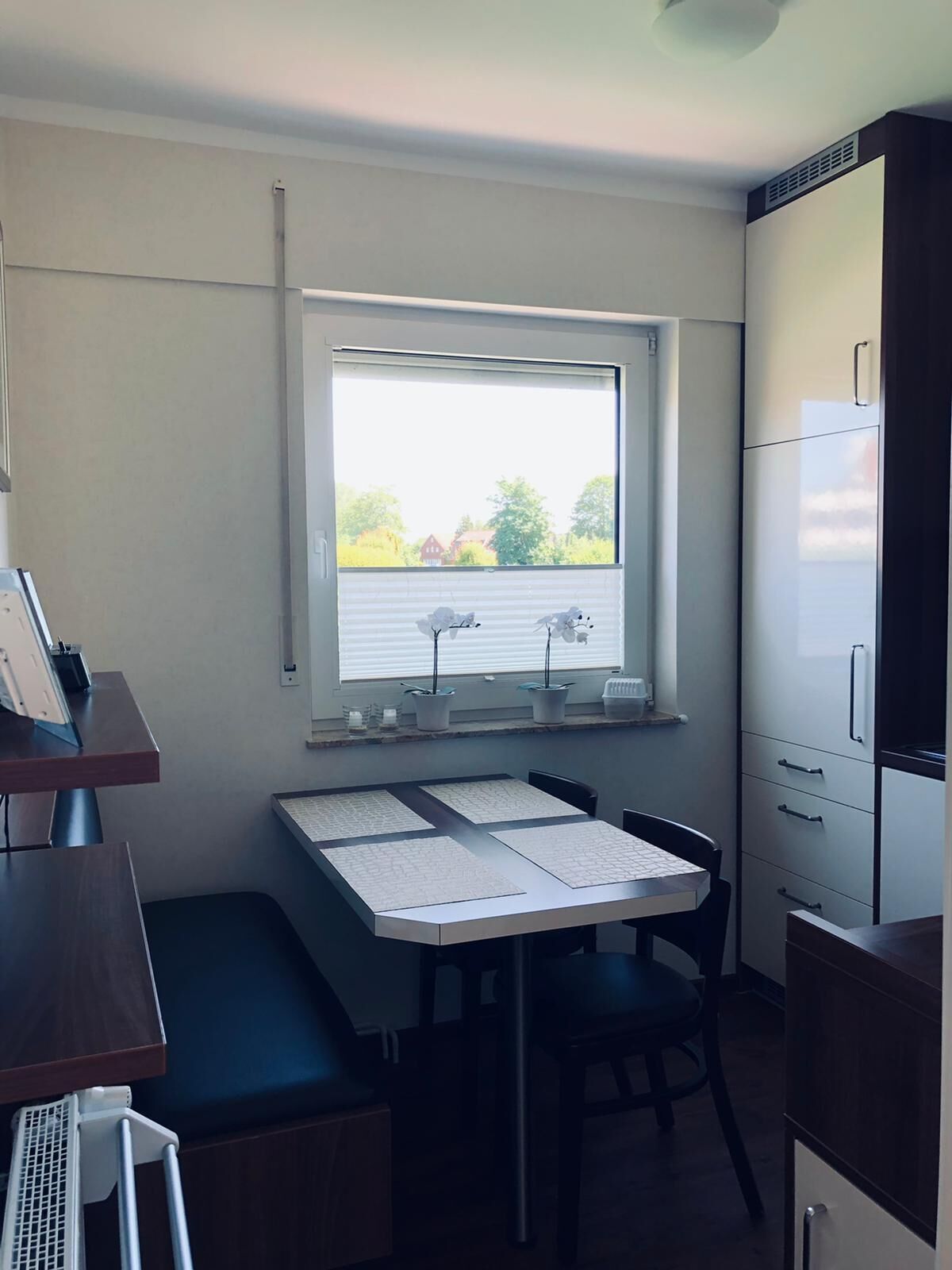 A compact kitchen with a window, a table with papers, and a refrigerator.