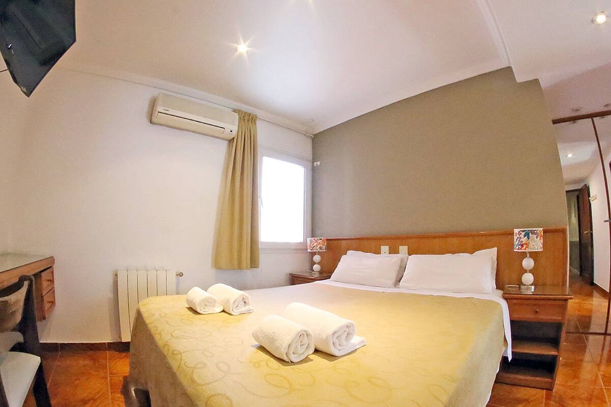 A hotel room with a large bed, a desk, and a window.