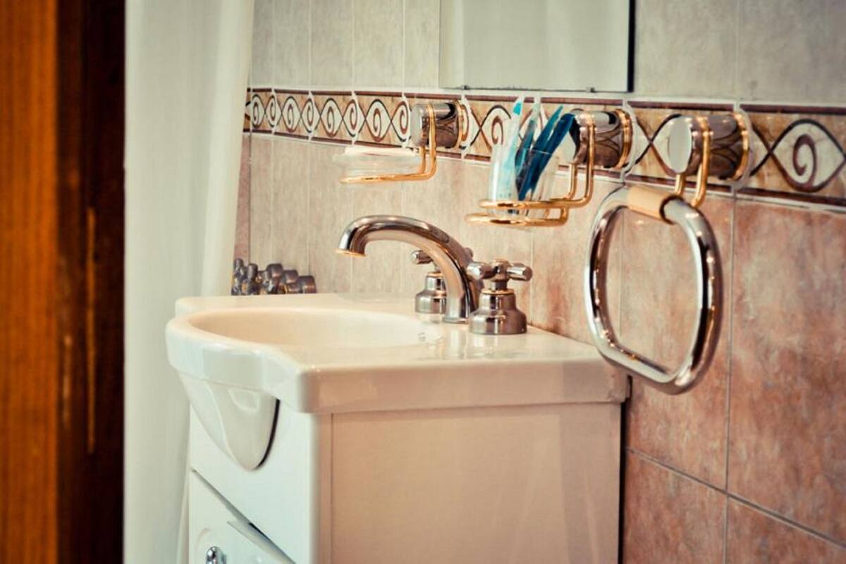 A bathroom with a sink, faucet, and towel rack.