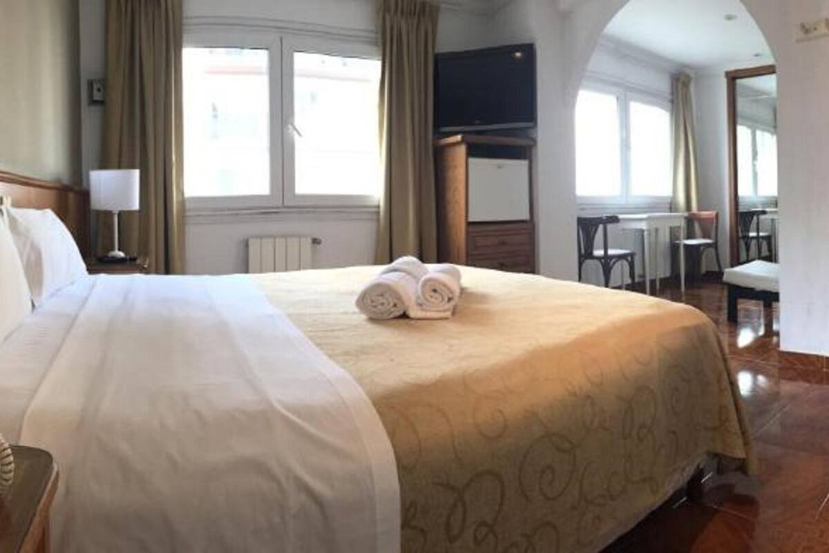 A hotel room with a large bed, a bedside telephone, and a television on the wall.