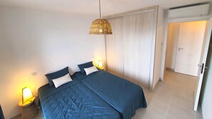 Une chambre à coucher comprenant un lit, des lampes de chevet, un luminaire suspendu, une armoire et une porte.