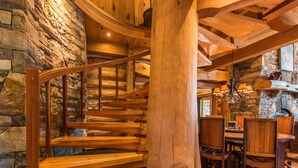 Un escalier en colimaçon en bois, avec des murs en pierre et un coin repas doté de meubles en bois.