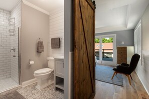 Un baño con ducha, inodoro y lavamanos, una puerta de madera y vistas al exterior.