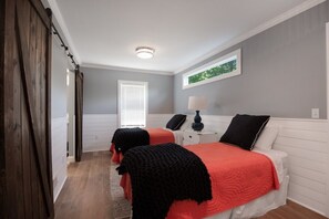 Un dormitorio con dos camas, una mesita de noche, una lámpara y una ventana con persianas.