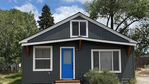 A small, two-story house with a dark exterior, a blue front door, and a small porch. - Newly Remodeled 4th Street Work-Friendly Home by RedAwning (Bend)
