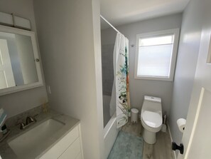 Bathroom features a sink, toilet, and shower with a floral-patterned curtain.