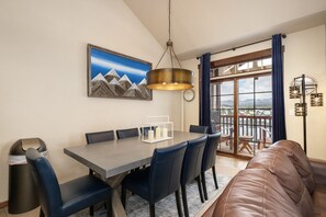 A dining area with a table, chairs, and a view through a large window. - Cozens Pointe I-101 2 Bedroom Condo by RedAwning (Fraser)