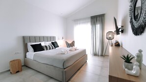 Un dormitorio moderno con cama, mesita de noche, lámpara y vistas al exterior.