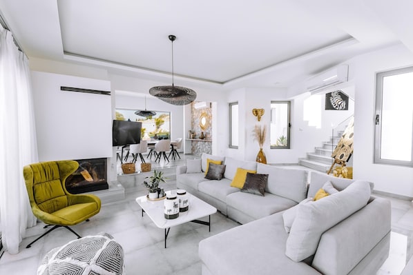 A modern living room with a sofa, armchair, coffee table, and artwork.