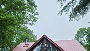 Een houten chalet met twee verdiepingen, een rood dak, grote ramen en een houten balkon.