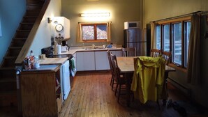 Een kleine keuken met een eethoek, houten vloeren, een ingebouwde magnetron en een koelkast.