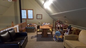 Een knus zolderkamer met een schuine hemel, een houten bed, een bureau en een boekenplank.