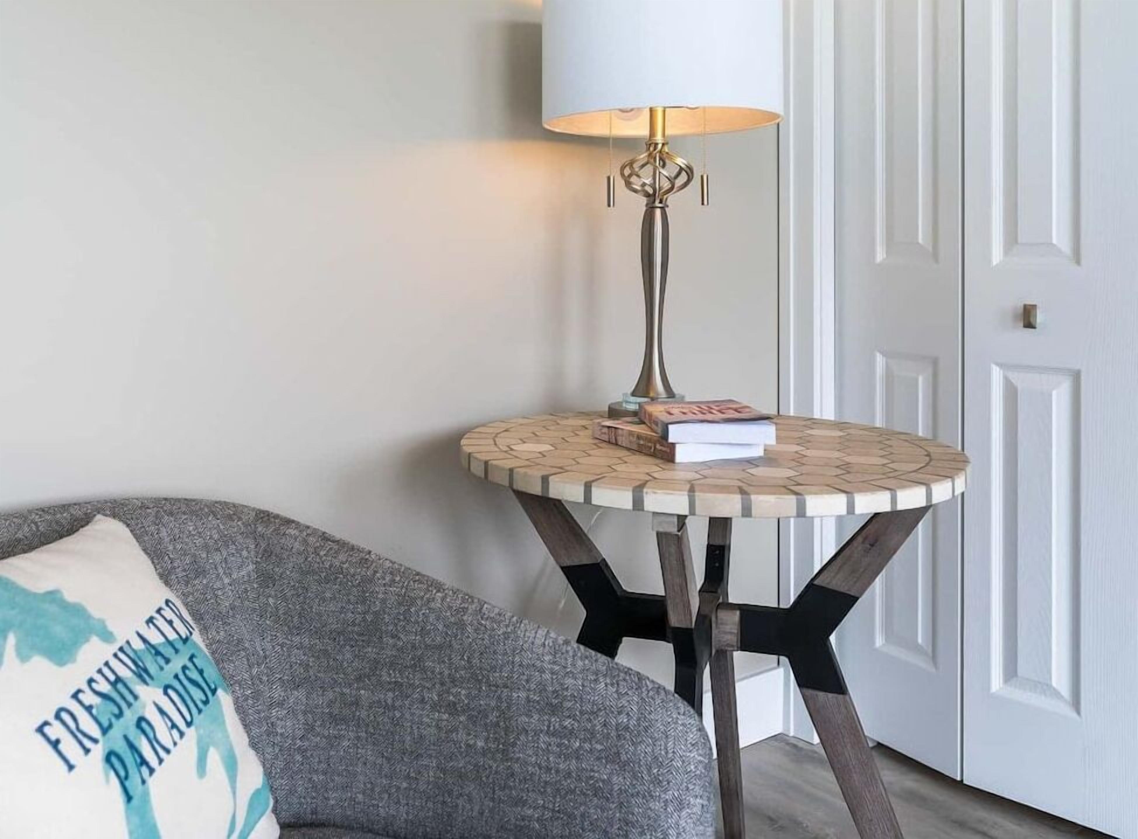 A room with a round side table, a lamp, a sofa, and a door.