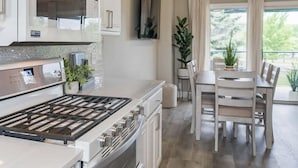 A modern kitchen with a gas stove, white cabinets, and a dining area with a table and chairs.