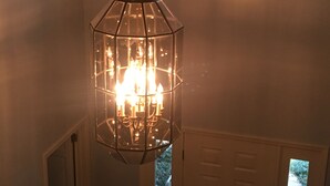 Un candelabro en un pasillo con vista a un jardín a través de una ventana sobre una puerta.