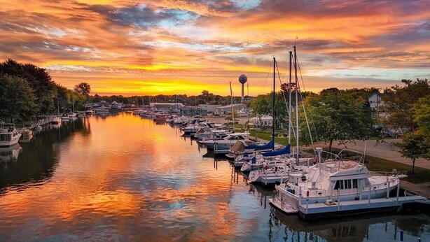 Un puerto deportivo con barcos amarrados a lo largo de un río al atardecer.