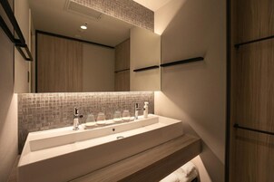 A modern bathroom with a large mirror, a white sink, and wooden cabinetry.