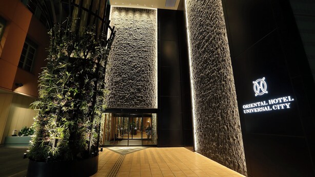 L’entrée de l’hôtel Oriental Hotel Universal City se distingue par son design moderne, avec un grand jardin vertical et une façade murale à motifs.