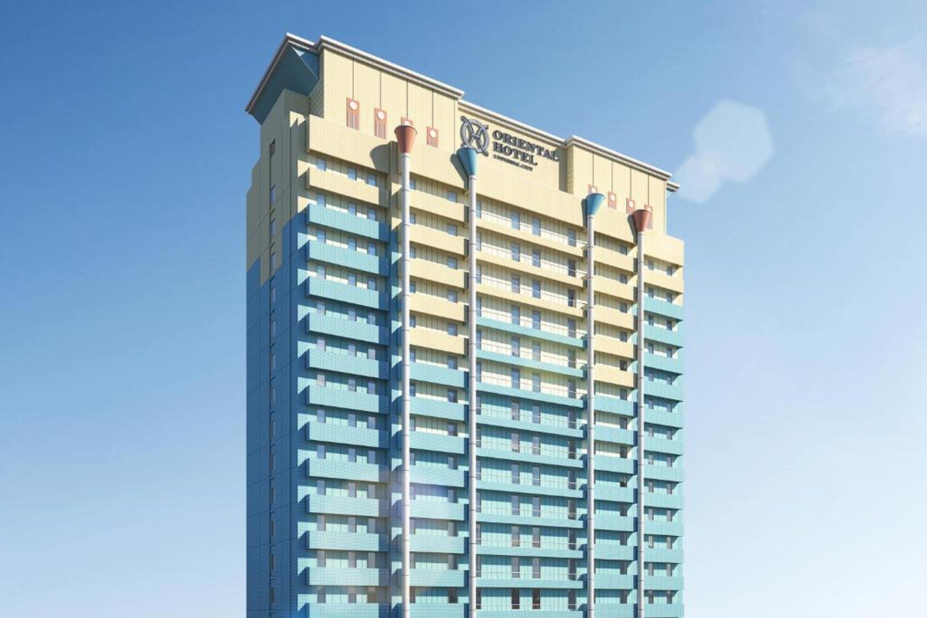 A tall hotel building with a modern design, featuring multiple balconies and a clear sky in the background.